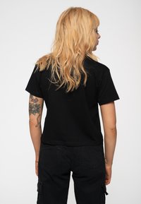 Black short-sleeve t-shirt with a relaxed fit. Smooth cotton fabric, round neckline, plain design, and no visible logos or patterns.