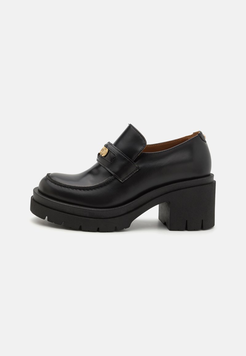 Schwarze Lederloafers haben eine hohe, klobige Plateausohle mit einer strukturierten Sohle. Sie verfügen über ein gesticktes Design und eine golden-farbene Akzentuierung am Riemen.