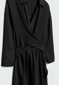 Vestido cruzado negro texturizado con cuello abotonado, mangas largas y cintura fruncida. Presenta una tela ligera y fluida.