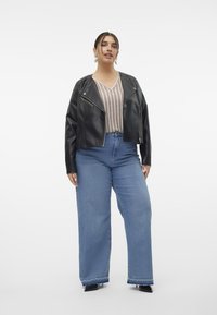Jachetă din piele neagră, scurtă, purtată peste un top bej cu dungi, asortată cu blugi denim de culoare albastră, cu picior larg. Denim-ul are margini desfăcute și o croială clasică.