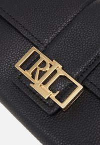 Musta nahkalaukku, jossa on teksturoitu pinta ja kultainen RLL-logo-solki. Rakenne, jossa on turvallinen läppäkoonus.