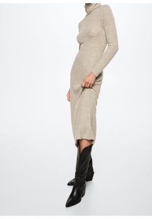 Beige ribbattu turtleneck mekko, slim fit, polvipituinen ja sivurei'ällä; yhdistetty mustiin nahkaisii teräväkärkisiin saappaisiin, joissa on keskipitkä varsi.