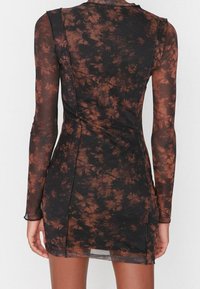 Abito aderente a maniche lunghe realizzato in tessuto nero trasparente con motivo floreale marrone. Presenta dettagli cuciti e un'orlo leggermente curvato.