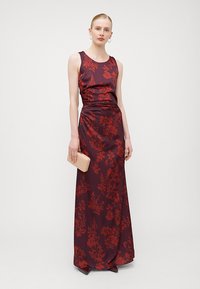 O rochie fără mâneci, burgundy, cu imprimeu floral, cu un corset adaptat și o fustă fluidă, completată de o poșetă dreptunghiulară roz deschis.