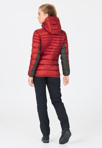 Rød og grå isoleret jakke med hætte, med en quiltet design. Sammen med sorte bukser og mørkt fodtøj.