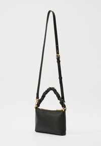 Black leather handbag with a braided handle and adjustable shoulder strap, featuring a gold zipper and smooth texture. Compact rectangular shape.