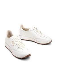 Sneakers bianche in pelle con punta rotonda, allacciatura frontale e un sottile design testurizzato. Suola in gomma con accenti di marrone chiaro. Dettaglio logo dorato.