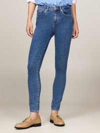Jeans ajustados de denim en color azul, con cintura alta, cinco bolsillos y detalles de costura sutiles. Combinados con mocasines beige.