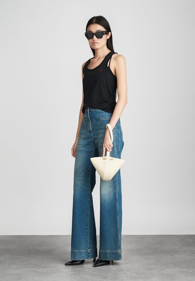 Melns bezufekts topiņš, augsto jostasvietu zilas džinsu bikses ar platu kāju un leņķa formas baltā rokassoma. Modelis nēsā melnus kvadrātveida saulesbrilles. Gludas tekstūras.