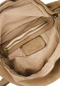 Beige leren handtas interieur met een katoenen voering, voorzien van een ritsvak en een label waarop staat "VENEZIA Echt Leer".