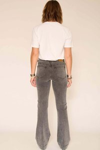 Jean flare gris avec une texture légèrement délavée, taille haute et deux poches arrière, associé à un t-shirt blanc uni.
