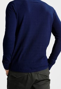 Maglietta a maniche lunghe blu marina con design aderente, polsi a coste e scollatura rotonda, realizzata in un tessuto leggero e liscio.