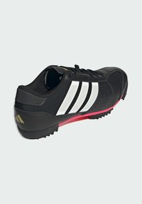 Schwarzer Sportschuh mit weißen Streifen, pinken Sohlenakzenten und strukturiertem Grip, von hinten und seitlich auf einem weißen Hintergrund gezeigt.