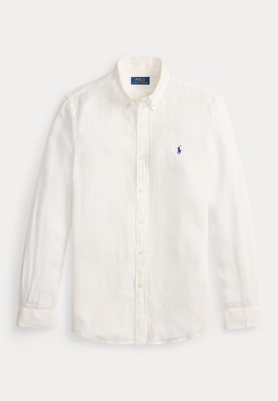 Camisa branca de linho, com botões e mangas longas, apresentando um colarinho clássico e um pequeno logotipo azul bordado no lado esquerdo do peito.