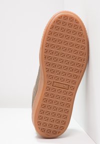 Baskets en daim marron avec une semelle intermédiaire texturée et une semelle extérieure en caoutchouc à motifs. Présente un logo de marque bien visible sur le côté.