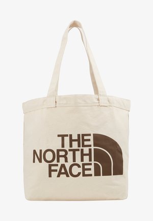 Beige canvas tote bag with two handles, featuring a large dark brown logo text "THE NORTH FACE" and a semi-circular design element.