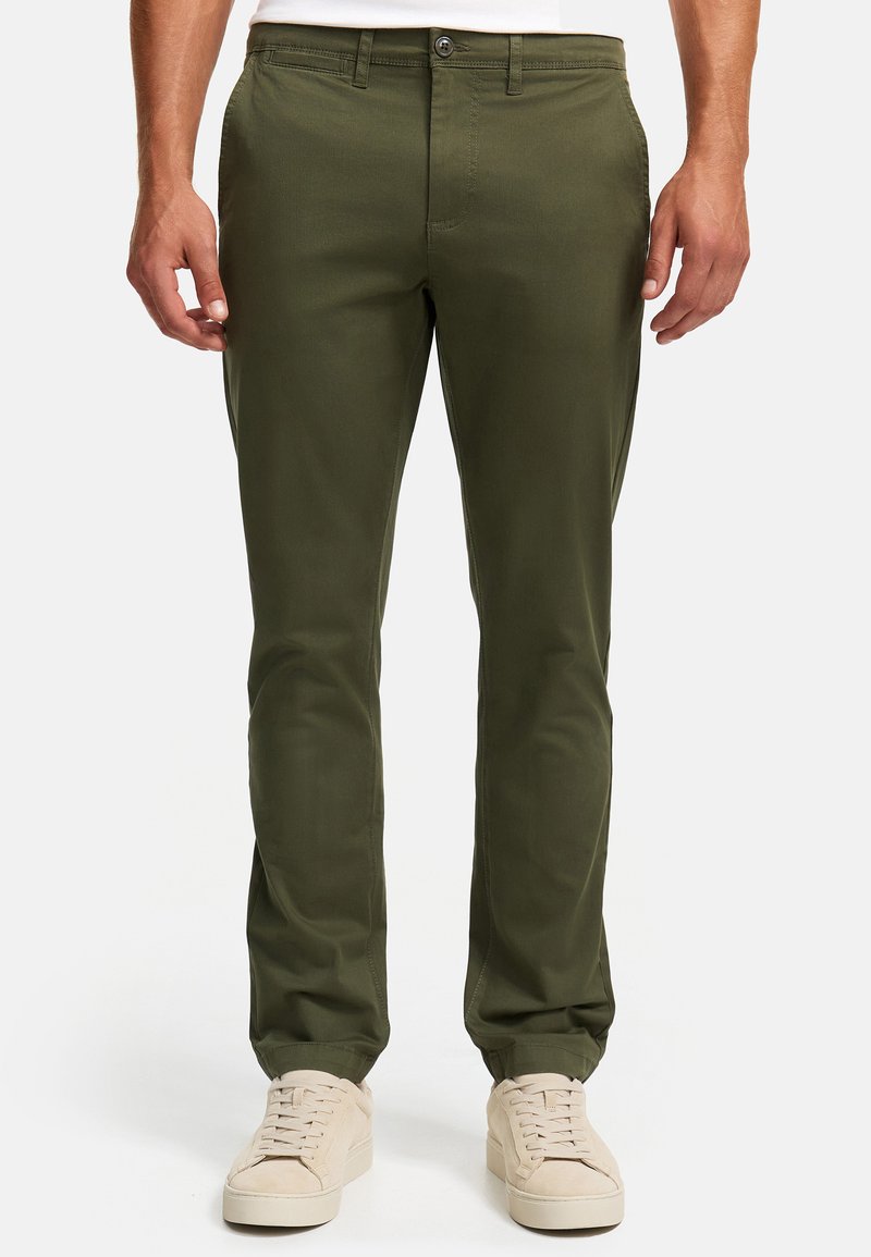 Chinos verde oliva con un diseño de pierna recta, hechos de un suave tejido de algodón, que cuentan con bolsillos frontales y un cierre de botón simple, llevados con zapatillas beige.