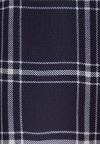 Tissu bleu foncé avec un motif à carreaux blanc composé de lignes droites et diagonales qui se croisent formant des carrés.