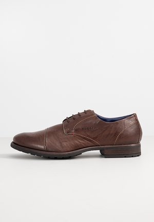 Brauner Leder-Herrenschnürschuh mit Kappzehe und gebrandetem seitlichem Detail, dunkler Sohle und niedrigem, gestapeltem Absatz.