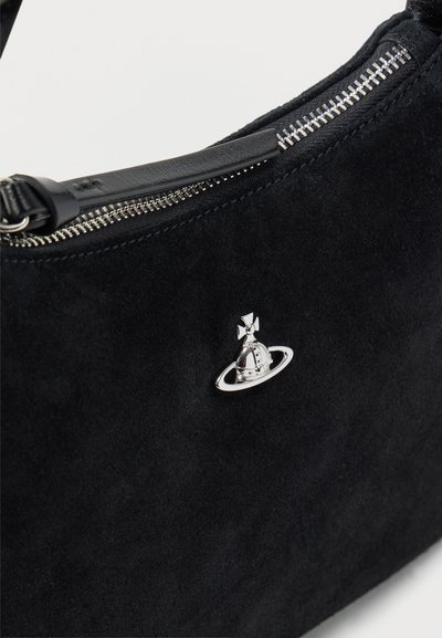 Μαύρη σουέντ τσάντα με ασημί φερμουάρ και ένα μικρό λαμπερό ασημένιο έμβλημα σε σχήμα σφαίρας και δαχτυλιδιού στο μπροστινό μέρος.