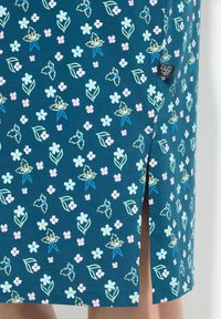 En teal blød stofkjole med et blomsterprint bestående af pink, hvide og blå blomster. Den har detalje med en sideslids.