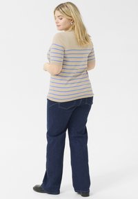 Beige raidallinen t-paita lyhyillä hihoilla yhdistettynä tummansinisiin farkkuihin. T-paidassa on sinisiä vaHorizontal stripes ja se on muotoiltu.
