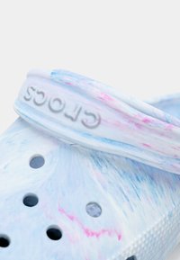Light blue and pink marbled Crocs with a textured surface, featuring ventilation holes and a branded strap around the heel.