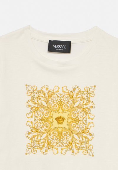 Majica v kremni barvi z okrašenim zlatim baročnim kvadratnim vzorcem s centralno glavo Meduze in črto etiketo Versace na ovratniku.