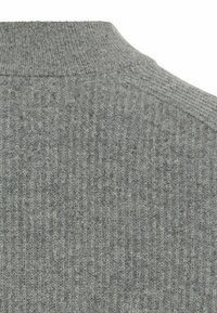 Grijs geribbeld sweaterstof met een hoge nek en een gestructureerd oppervlak. Kenmerkt subtiele variaties in schaduw en een openbreid ontwerp.