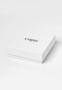 Weißer rechteckiger Kasten mit glatter Oberfläche. Der Deckel trägt das Wort "CHRIST" in fetter schwarzer Schrift, darunter steht "seit 1863".
