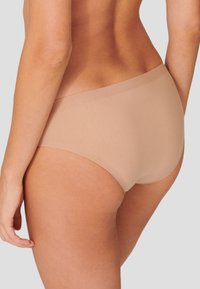 Beige nahtlose Unterwäsche mit glatter Textur, hochgeschnittenem Design und weichem Bund, aus einer Seitenansicht vor einem neutralen Hintergrund gezeigt.