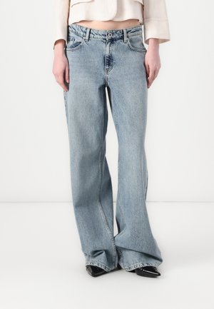 Lyseblå vidbukser laget av denim. Har høy midje, frontlommer og subtil fading. Kombinert med svarte spisse sko.