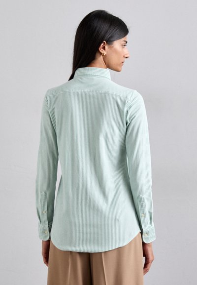 Camicia a righe verde chiaro con maniche lunghe, polsini con bottone e spallina sul retro. Texture liscia e colletto classico, vestibilità sagomata.