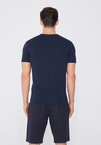 Námořnická modrá trika s krátkým rukávem a kulatým výstřihem vyrobená z bavlny. Jednoduchý design, hladká textura, bez viditelných vzorů nebo akcentů.