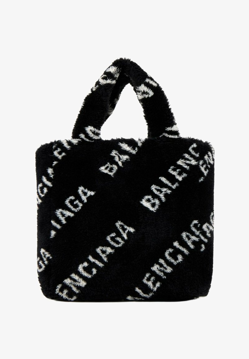 Sac cabas noir en fausse fourrure avec des poignées courtes, arborant un texte blanc « Balenciaga » répété et imprimé en diagonale sur la surface.