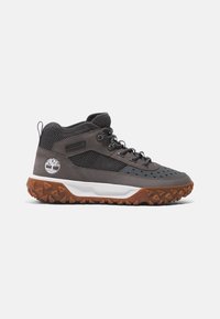Graue High-Top-Schuhe aus Mesh und synthetischen Materialien, mit einer weißen Zwischensohle und einer strukturierten braunen Gummisohle mit einem Baum-Logo.