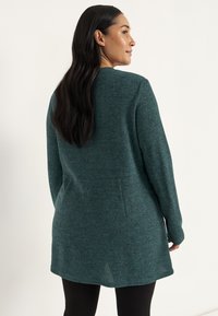 Teal gebreide cardigan met lange mouwen, een rechte snit en zijsplitten. Textuurstof met een zachte afwerking. Achteraanzicht weergegeven.