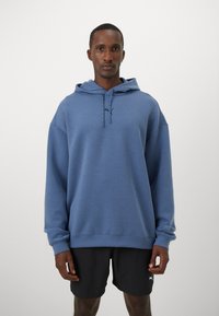 Blå hoodie lavet af blødt stof, med en kængurulomme, snore og et lille logo. Lange ærmer med en afslappet pasform.