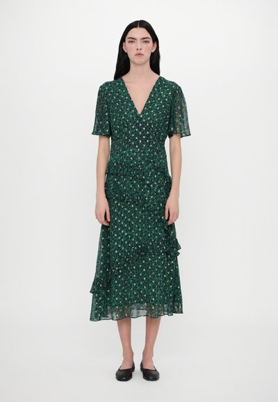 Zelené šaty se vzorem leopardí kůže, s výstřihem do V, krátkými rukávy a volánovým lemem. Vyrobené z lehké látky, mají přiléhavý pas a splývavou siluetu.
