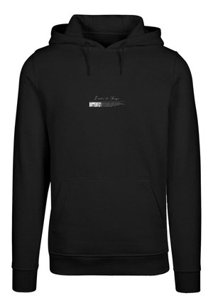 Juodas kapučinas, pagamintas iš minkštos medžiagos, su priekiu įsisegtu kišeniu, su raišteliu galvai ir baltu grafiniu spausdinimu su žodžiu "KOVAS".