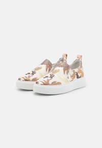 Slip-on boty vyrobené z vzorované látky v béžových, hnědých a zelených odstínech, s bílou podrážkou a patou pro snadné nošení.