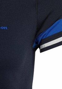 Camiseta atlética en azul marino con tejido que absorbe la humedad. Presenta rayas azules y blancas en las mangas y un logotipo azul en el pecho.