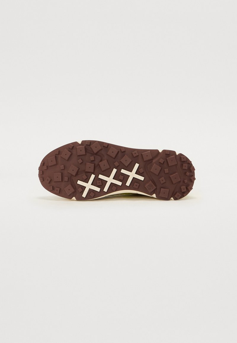 Semelle en caoutchouc marron avec un motif texturé ; présente trois croix blanches et des formes géométriques mélangées pour une meilleure adhérence.