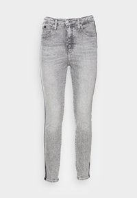 Grå denim skinny jeans med en föråldrad finish, femfickorsdesign och svarta sidestreck. Har dragkedja och knappstängning.