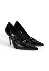 Schwarze High Heels aus Lackleder mit spitzer Schuhspitze, schlankem Stiletto-Absatz und dekorativem Schnallendetail vorne. Glatte Textur.