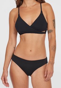 Set bikini nero con top a wrap con spalline sottili e parte bassa a vita bassa. Tessuto liscio con cuciture minime e senza motivi.