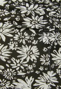 Tela negra con un patrón floral blanco de flores de diferentes tamaños y formas, sobre un fondo texturizado.