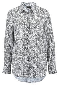 Svart och vitprickig långärmad skjorta med knappar fram, krage och uppvikta ärmar, tillverkad av lätt tyg med en slät yta.