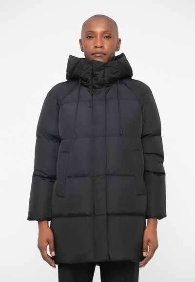 Schwarze Pufferjacke mit hohem Kragen, langen Ärmeln, großen Taschen und boxy Form. Glatte, isolierte Stoff mit matter Oberfläche.
