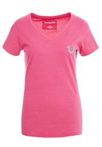 Camiseta de algodón rosa con diseño de cuello en V. Presenta un pequeño logotipo gris en el lado izquierdo del pecho. Textura suave, mangas cortas y un ajuste relajado.